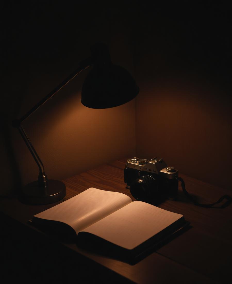 Lamplit desk with notebook and vintage camera.